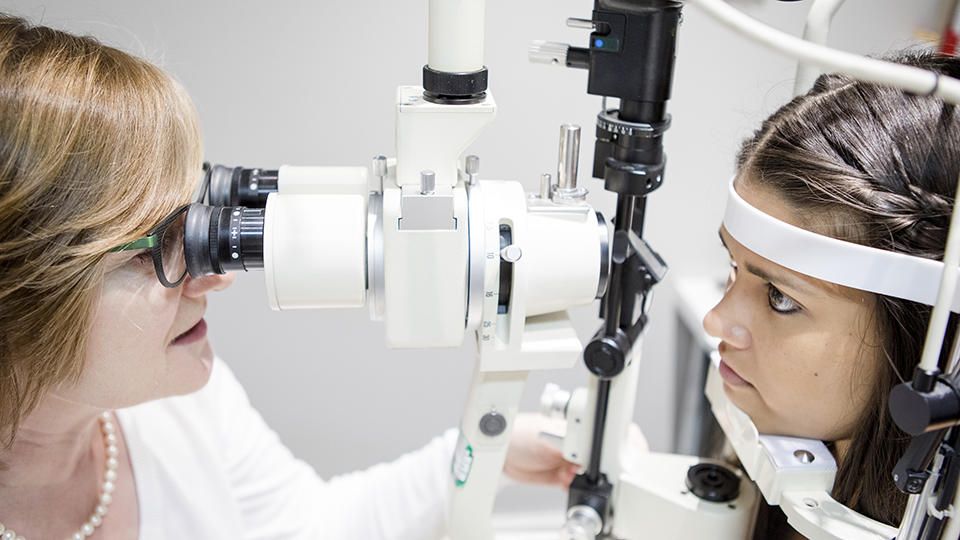 Optometrist examining patients' eyes with optometer