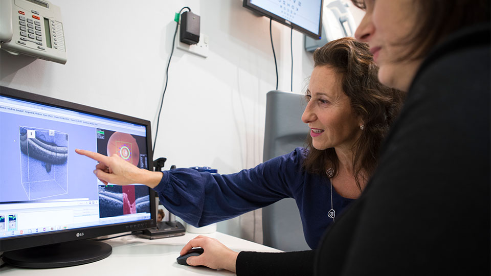 Two optometrists looking at results of an eye test on a computer screen