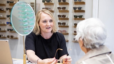 Optometrist with patient looking at spectacles