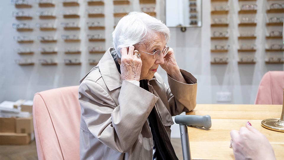 An elderly lady trying on a pair of spectacles
