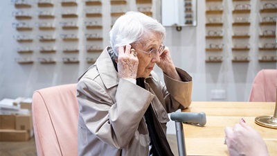 An elderly lady trying on a pair of spectacles