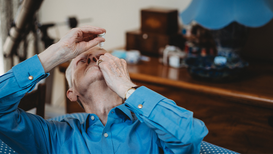 A man putting eye drops in his eyes