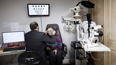 A male optometrist looking at a female patients eyes
