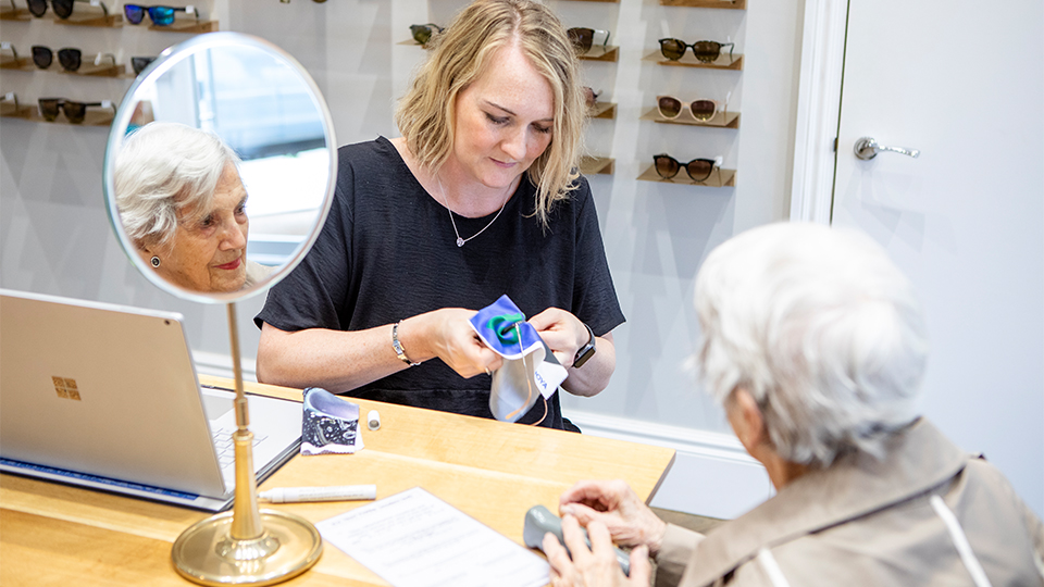 Optometrist is cleaning patient's spectacles at practice