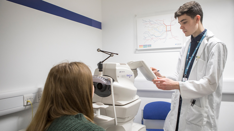 Optometrist examining child's eyes with an optometer