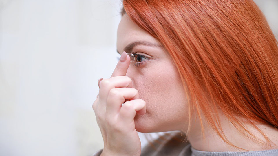 A woman putting a contact lens into her eye