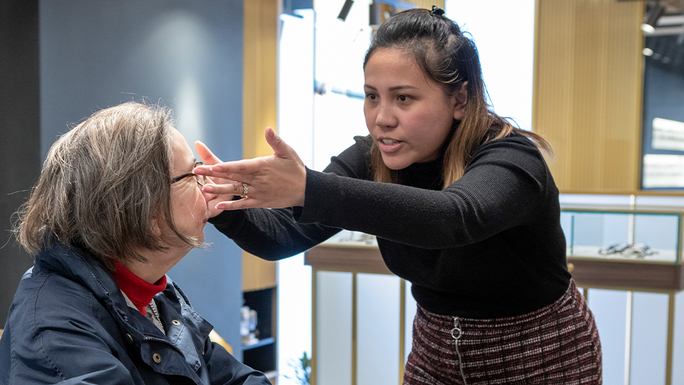 Optometrist is examining elderly woman's eyes
