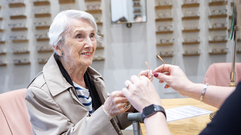 Older people with optometrist trying on spectacles