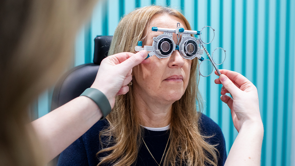 Optometrist using an optometer to measure woman's eyes