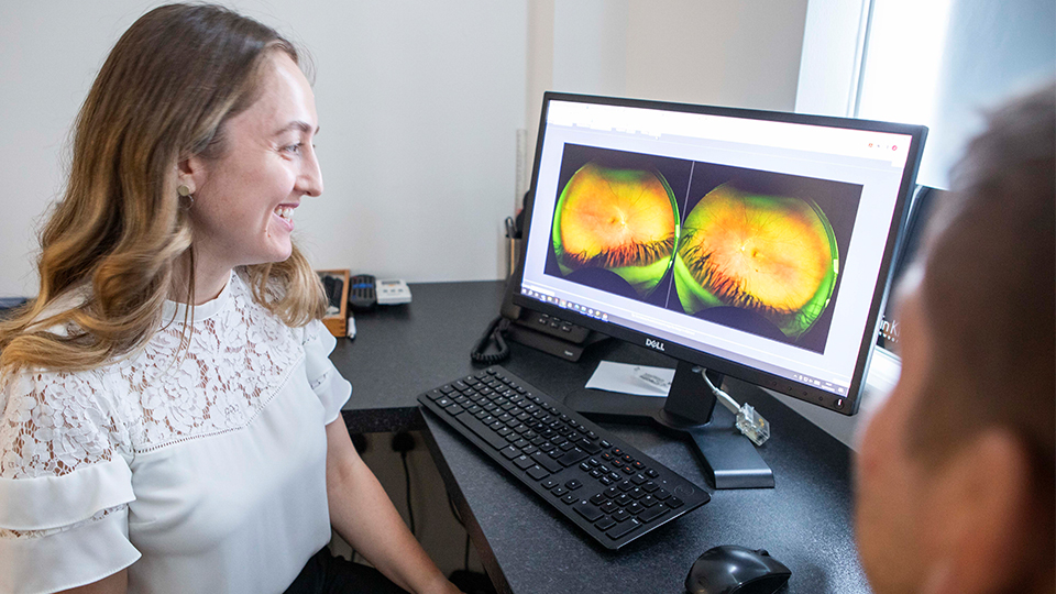 Optometrist with patient looking at computer screen of his eyes