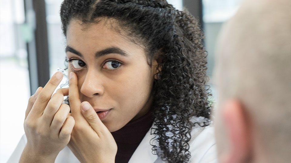 Woman putting a contact lens into her right eye