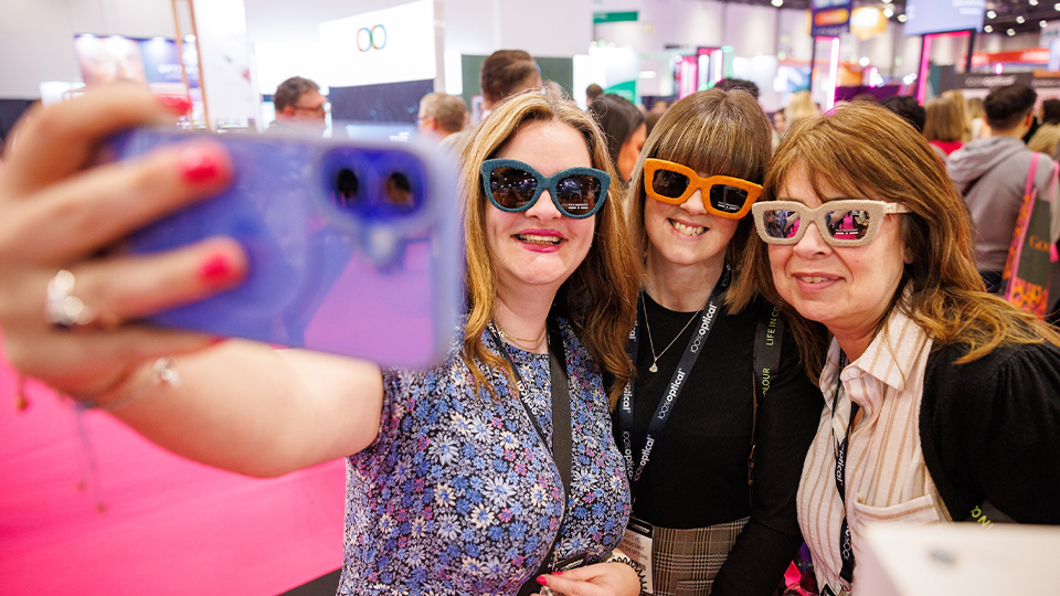 Three women pose together in sunglasses for a selfie at 100% Optical