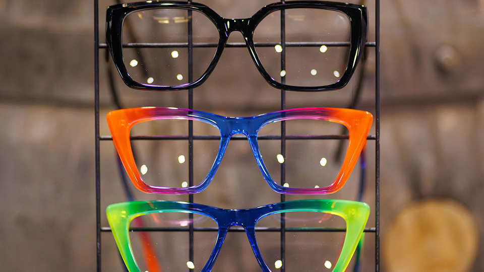 A line of colourful spectacles arranged one above the other and lit from behind
