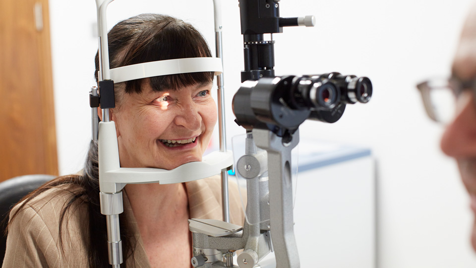 Lady smiling sitting having her sight tested