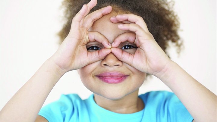 Young children makes glasses shape with her hands