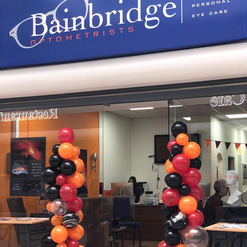 The store front of the Bainbridge practice with red, black, orange and marbled balloon arches around the door