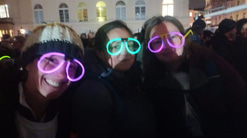 Three walkers, wrapped up warm, pose in a blurry photo with glow-in-the-dark glasses in teal and purple