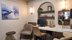 A private consulting and dispense room at Boots Opticians Wigmore. The walls are a soft cream-grey marble style, furnishings are beige, there is a panelled arch shelving display, and a large painting on the wall. The feeling is spa-like and calm