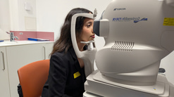 An optometry student is seated at a optical coherence tomography machine as a test patient