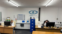 Members of staff in the DSW Optical office, smile to each other, one on the phone