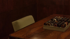 A dark room with wooden walls and a wooden table with a display tray of trial lenses. A paper lampshade hangs low above it