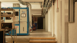 A long wing of a building with optical equipment on the left hand side including a lens edger machine