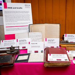 Braille items from RNIB's archive organised on a table at the Braille 200 British Library event