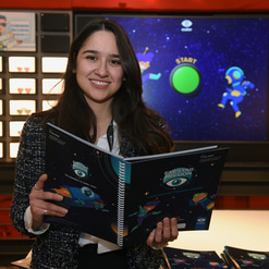 Gizem Topdagi holds open a booklet from the Eyestar Mission educational programme