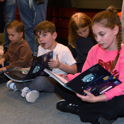 Three children read through the booklets