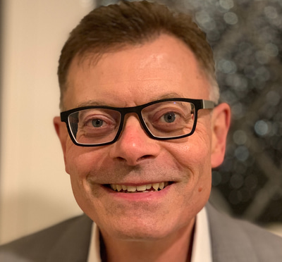 Martyn Howlett wears a white shirt and tan suit jacket