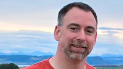 Raymond Ellis smiling in a red t-shirt