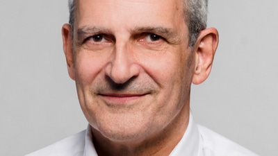 A corporate photo of Marius wearing a white shirt without tie, smiling gently at the camera