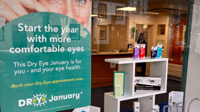 An optometry practice window with a large poster promoting the dry eye campaign and a display of dry eye products, tools, and information