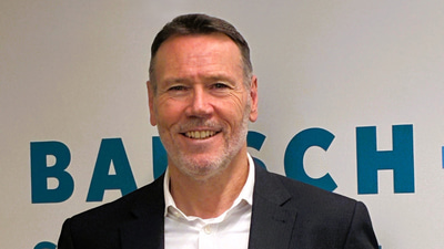 Mark Draper stands in a Bausch + Lomb office wearing a suit