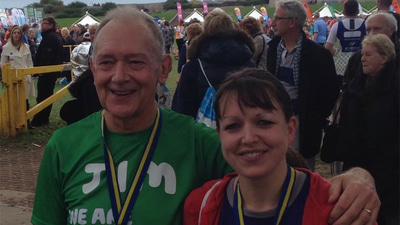 Jim Tassell and Emma Damen are shown wearing athletic clothing and medals, smiling at the camera
