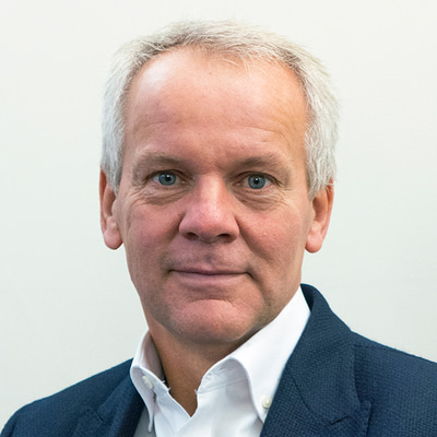 David Cartwright smiles at the camera wearing a navy suit