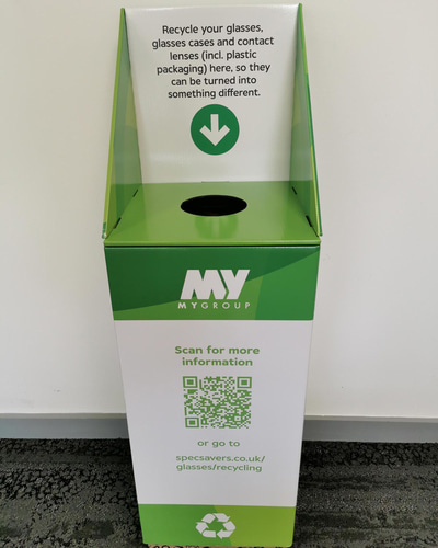 A green collection box with ‘MyGroup’ labels and a sign advising: “Recycle your glasses, glasses cases and contact lenses (including plastic packaging here) here, so they can be turned into something different