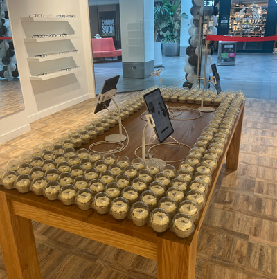 A wooden table in the centre of the practice has four tablets set up on stands, displaying a page of frame information. 