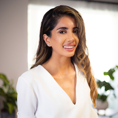 Jasmin Matharu smiling looking into the camera. She is wearing a v-neck white shirt.