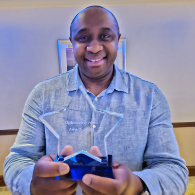 Optometry Hero Award recipient, Jude Edwards, holding a award in his hands 