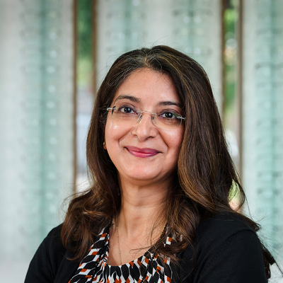 Woman wearing glasses with long brown hair, smiling