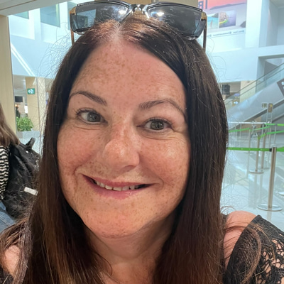 Nikki smiles broadly, wearing black with sunglasses pushed on top of her head