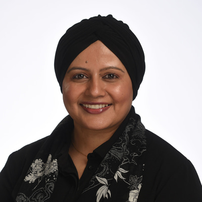 Woman smiling wearing a black head scarf and a black top.