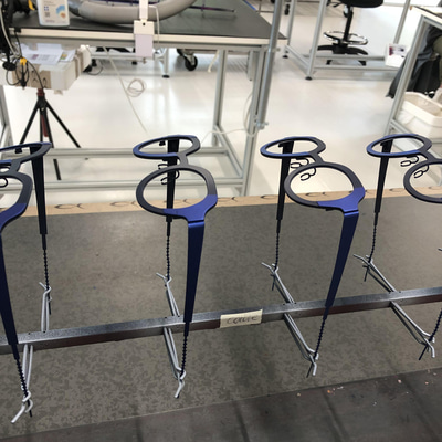 A line of spectacle frames are attached to one pole. The frames are made of titanium and sprayed in two tones of dark and light blue
