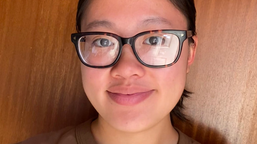 Zi Yu smiles directly to the camera, wearing squared frames in a dark tort colorway and a baseball style shirt in brown and white