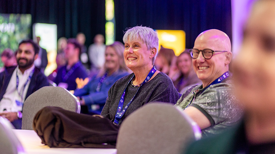 Two people sit at a conference table laughing