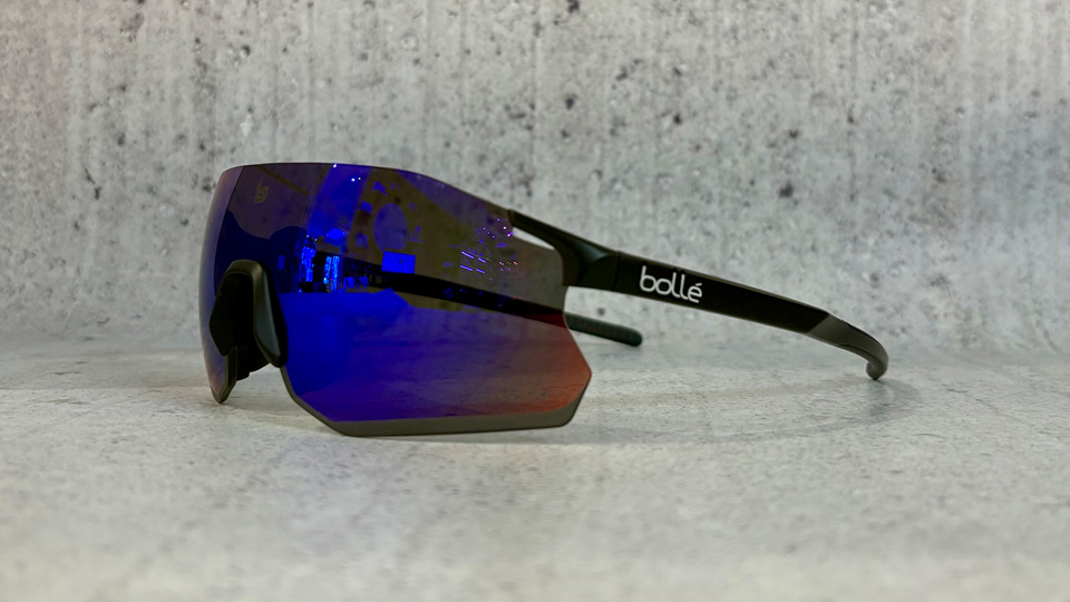 A side-on view of some sports frames with large shield lenses in a blue-purple colour, and thin arms in black