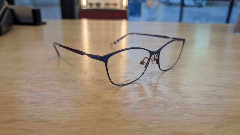 A pair of super-fine tianium spectacles in a deep blue. The arms of the frame feature a twist, displaying the purple colouring of the underside of the metal arms