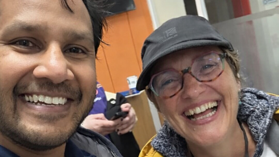 Two people pose together in coats and branded Vision Care t-shirts, they are smiling and excited