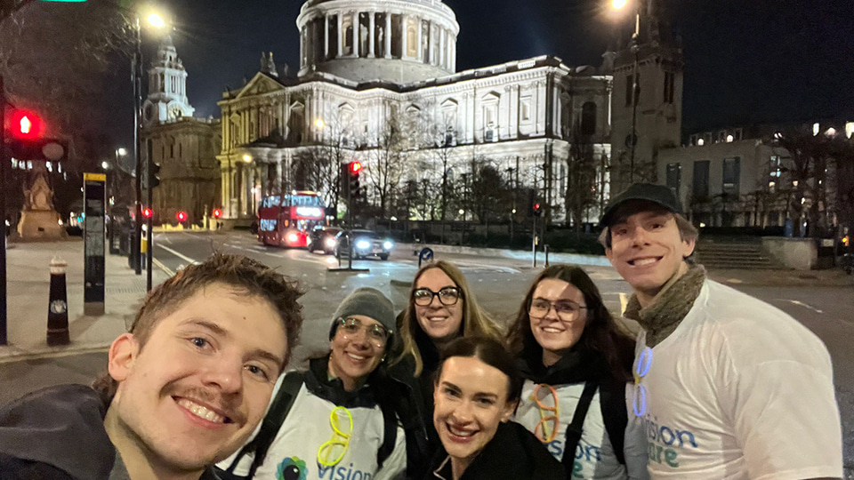 Six people lean in for a selfie outside of St Pauls Cathedral on the London Walk at night